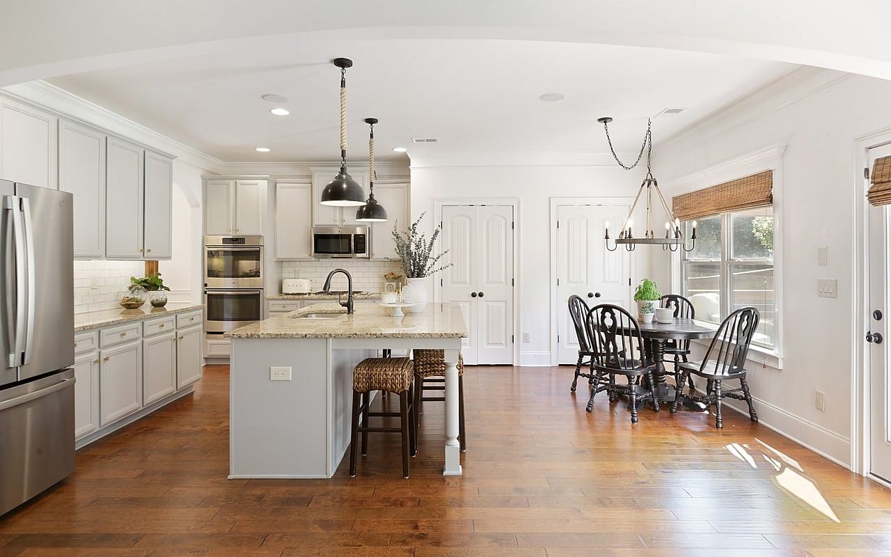 After: bright white kitchen with an island, pendant lights and hardwood floors