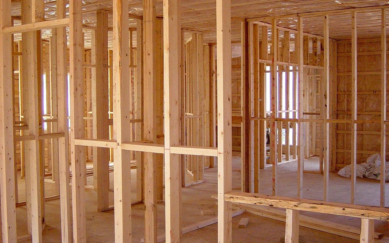 Before: a room with bare wood stud framing and open window frames