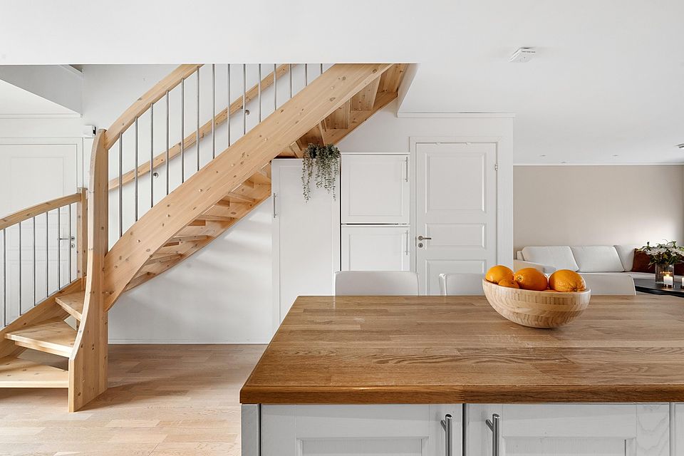 Light oak open staircase beside a kitchen island with a butcher-block top