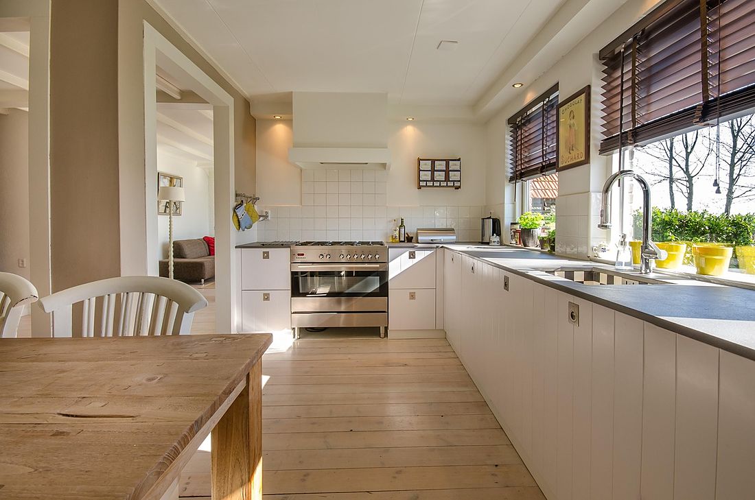 Long bright kitchen with white cabinets, a window wall and oak floors