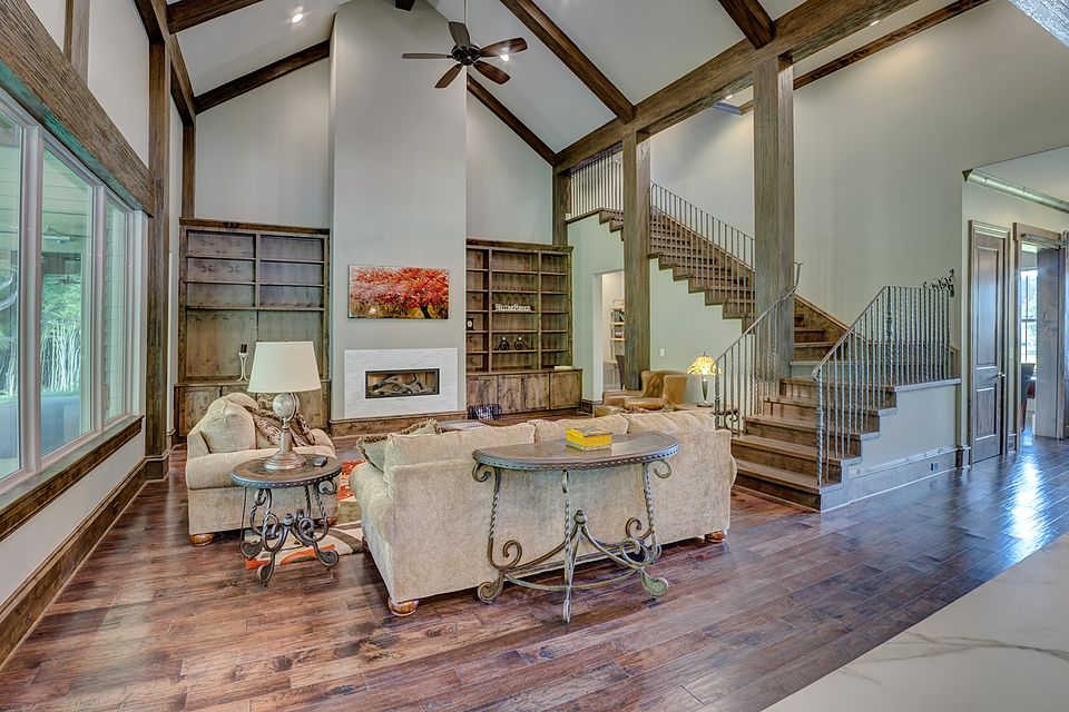 Open great room with a vaulted timber ceiling, stone fireplace and staircase
